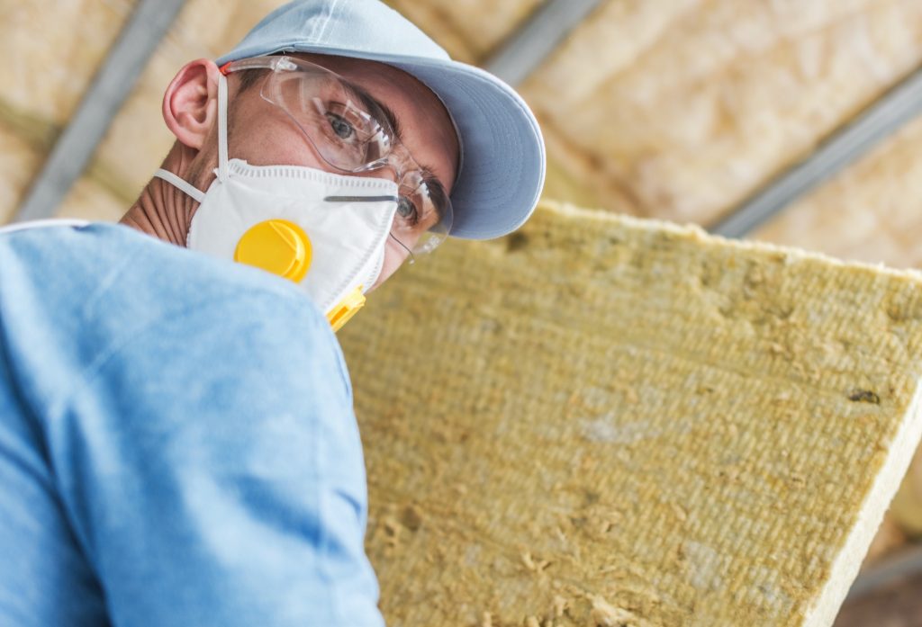 Contractor Worker with Piece of Mineral Wool Home Insulation Material